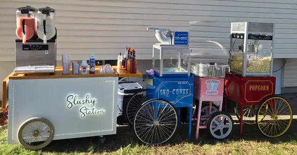 Slushy station, snow cone, cotton candy and popcorn carts lined up in a back yard