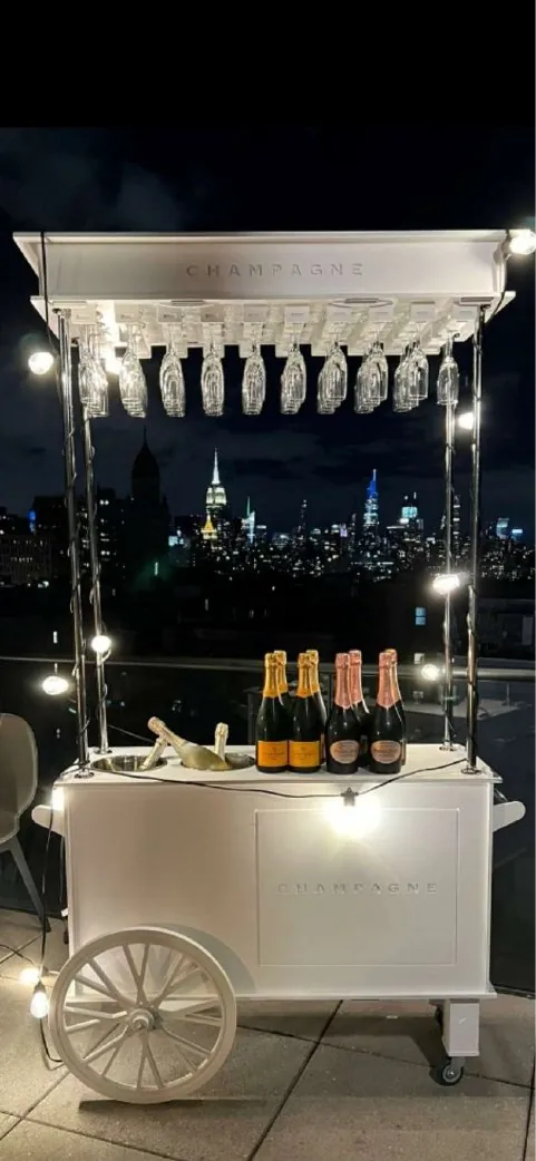 White champagne cart with hanging glasses and lights at night