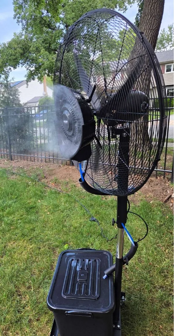 Outdoor misting fan with water tank on a lawn