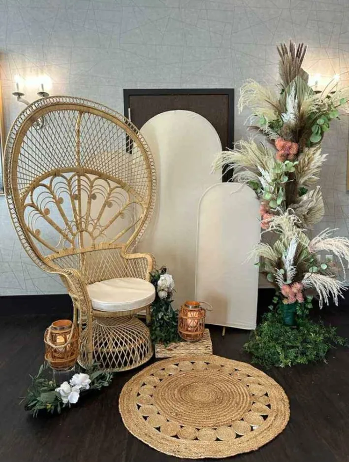 Rattan peacock chair with cream cushion, arches and pampas decor