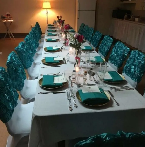 Long rectangular table set for dinner with teal napkins