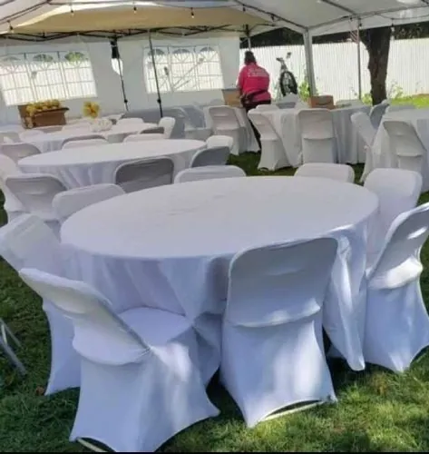 Round tables with white linens and covered chairs under a tent